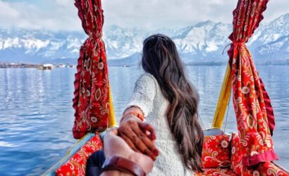 Anniversary couple holding hands while enjoying a romantic Kashmir holiday package amidst scenic dal lake | Panda Tours and Travels