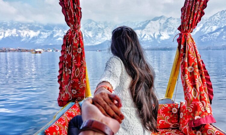 Anniversary couple holding hands while enjoying a romantic Kashmir holiday package amidst scenic dal lake | Panda Tours and Travels