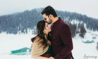 Anniversary couple enjoying snow around with a loving forehead kiss during a Kashmir holiday package | Panda Tours and Travels