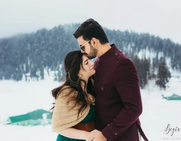 Anniversary couple enjoying snow around with a loving forehead kiss during a Kashmir holiday package | Panda Tours and Travels