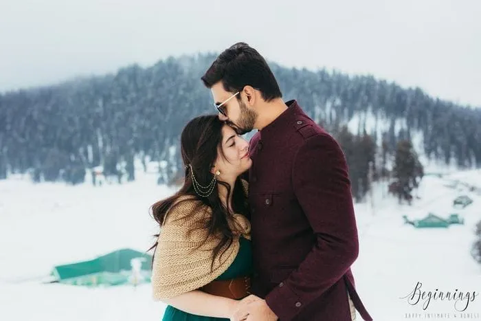 Anniversary couple enjoying snow around with a loving forehead kiss during a Kashmir holiday package | Panda Tours and Travels