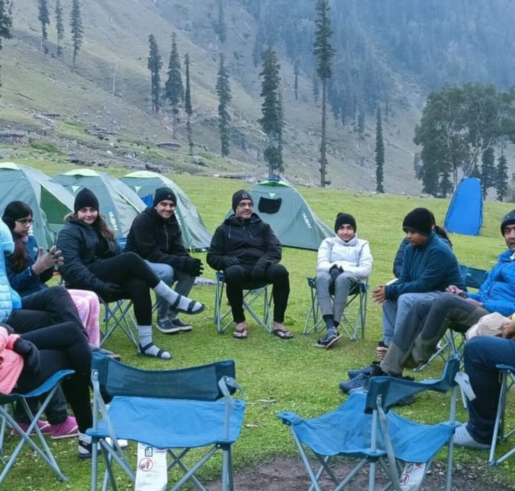 Trekkers relaxing on chairs at campsite during Kashmir Great Lakes Trek in Himalayan valley