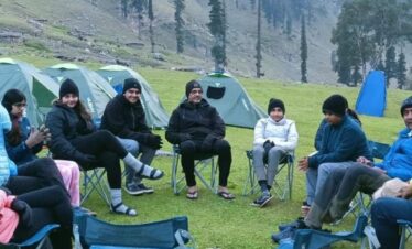 Trekkers relaxing on chairs at campsite during Kashmir Great Lakes Trek in Himalayan valley
