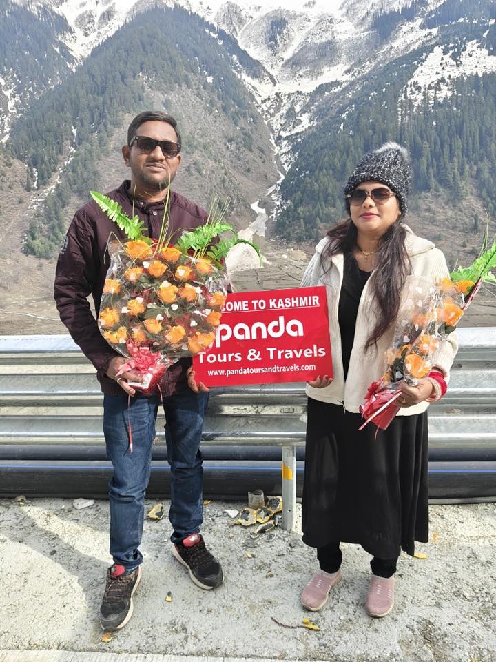 Happy guests holding Panda Tours and Travels welcome board during their Kashmir trip