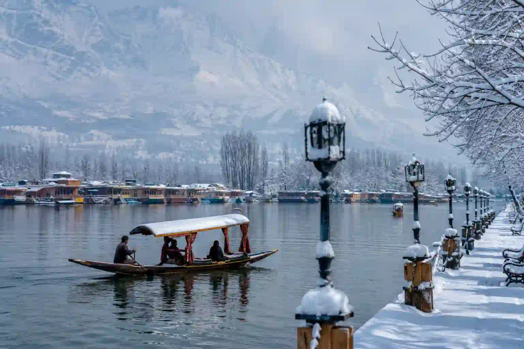 Snow-covered Dal Lake in Srinagar Kashmir with a shikara, houseboats and snow-capped mountains