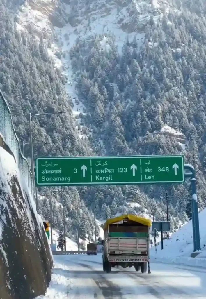 Snow-covered road near Sonamarg with a sign pointing toward Kargil and Leh in winter Kashmir.