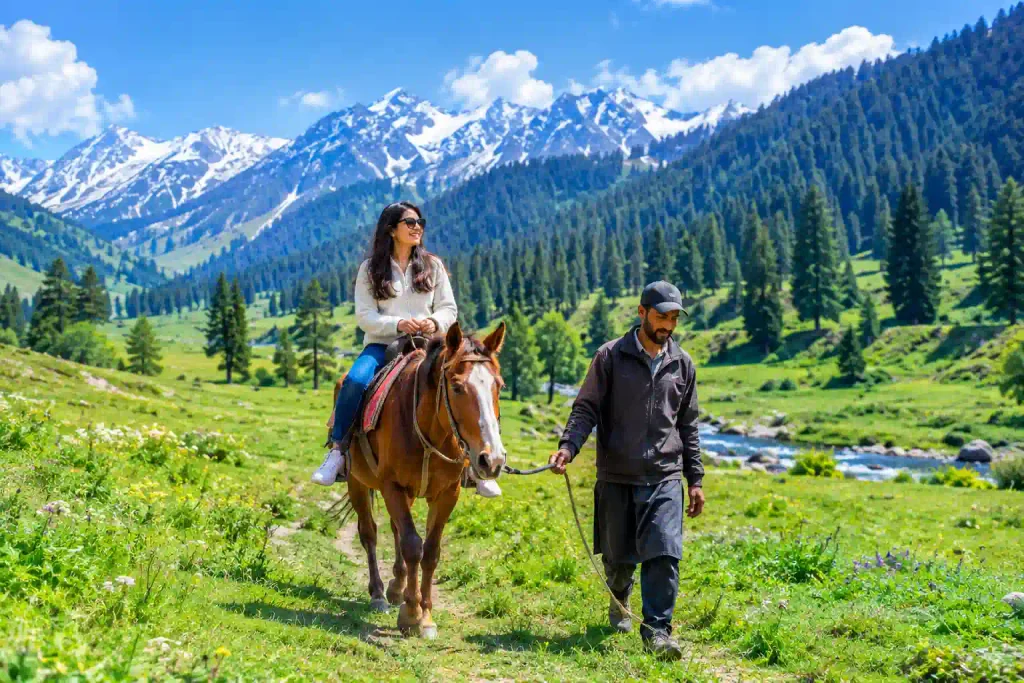 How to Reach Yusmarg from Srinagar 2 Tourist enjoying horse riding in Yusmarg surrounded by lush green meadows, pine forests, and Himalayan mountains in Kashmir