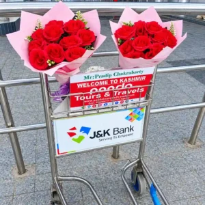 Panda Tours and Travels welcome board and red rose bouquets on a luggage trolley at Srinagar Airport